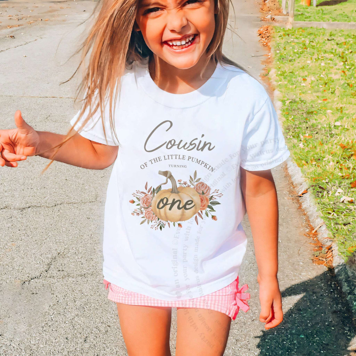 Laughing girl outdoors in a white Cousin of the Little Pumpkin kids tee.