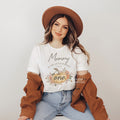 Smiling woman in a brown hat wearing a Mommy of the Little Pumpkin shirt with a rustic pumpkin.
