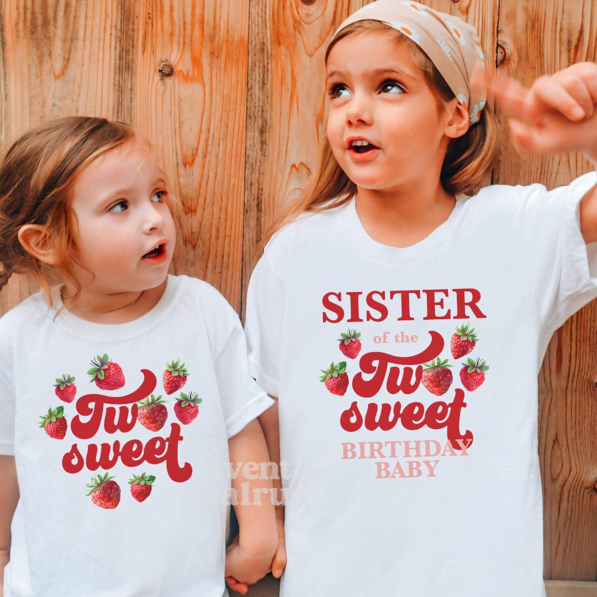 Two girls against a wood wall in white strawberry Two Sweet and Sister shirts.