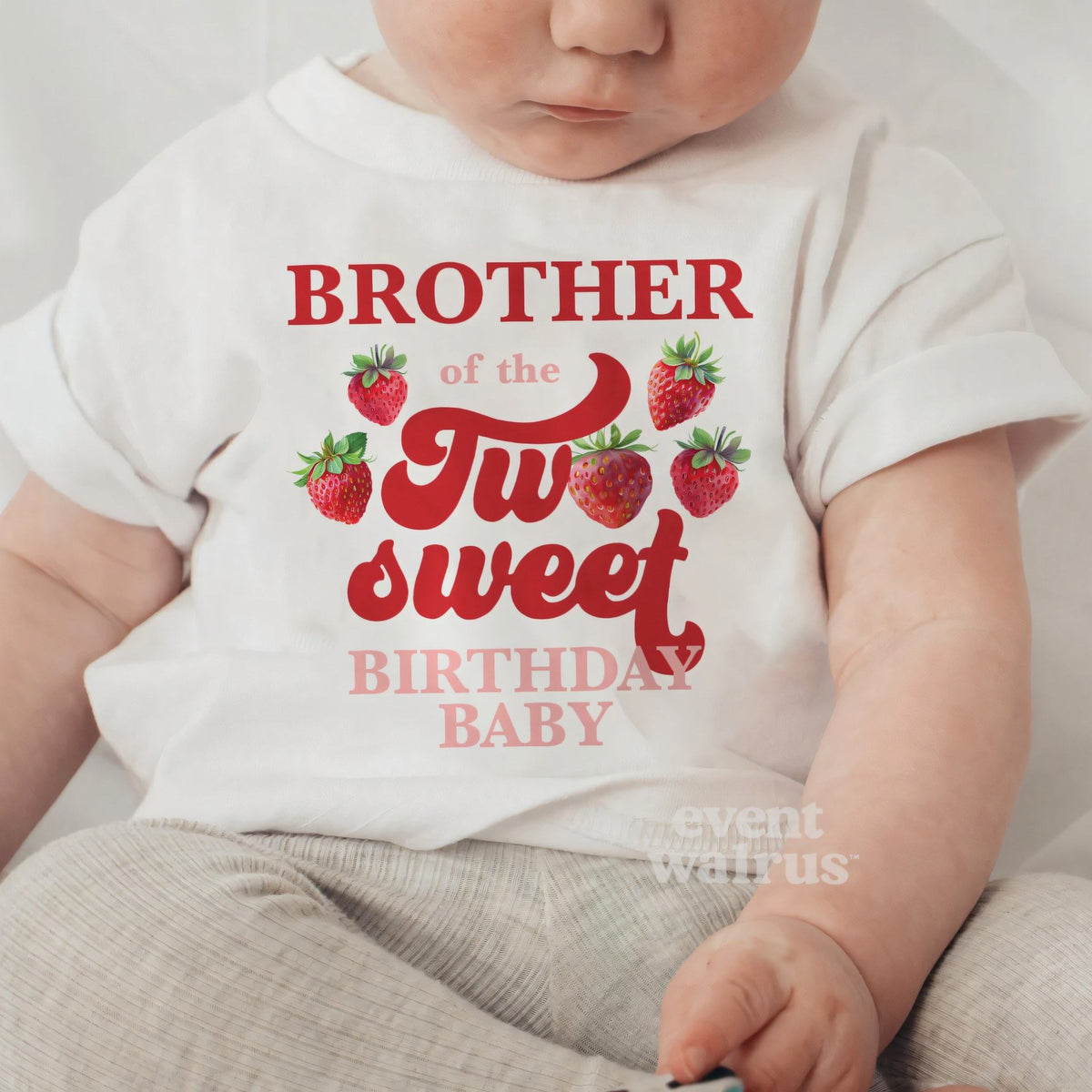 Baby sitting up in a white Brother of the Two Sweet baby tee.