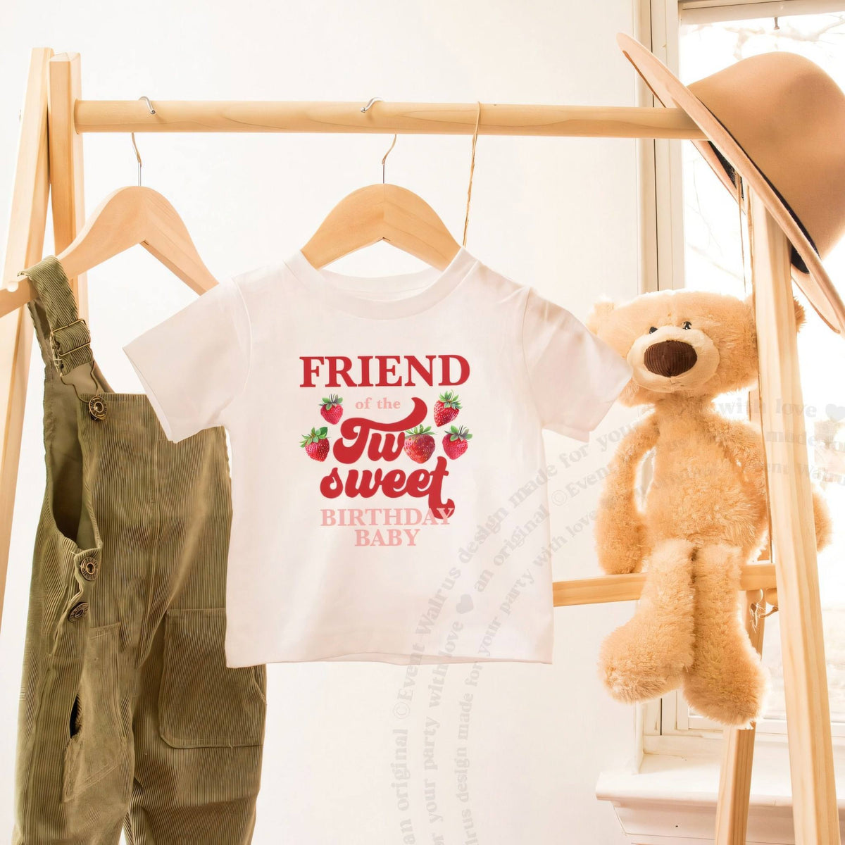 White Friend of the Two Sweet toddler tee on a wooden clothes rack beside a teddy bear.