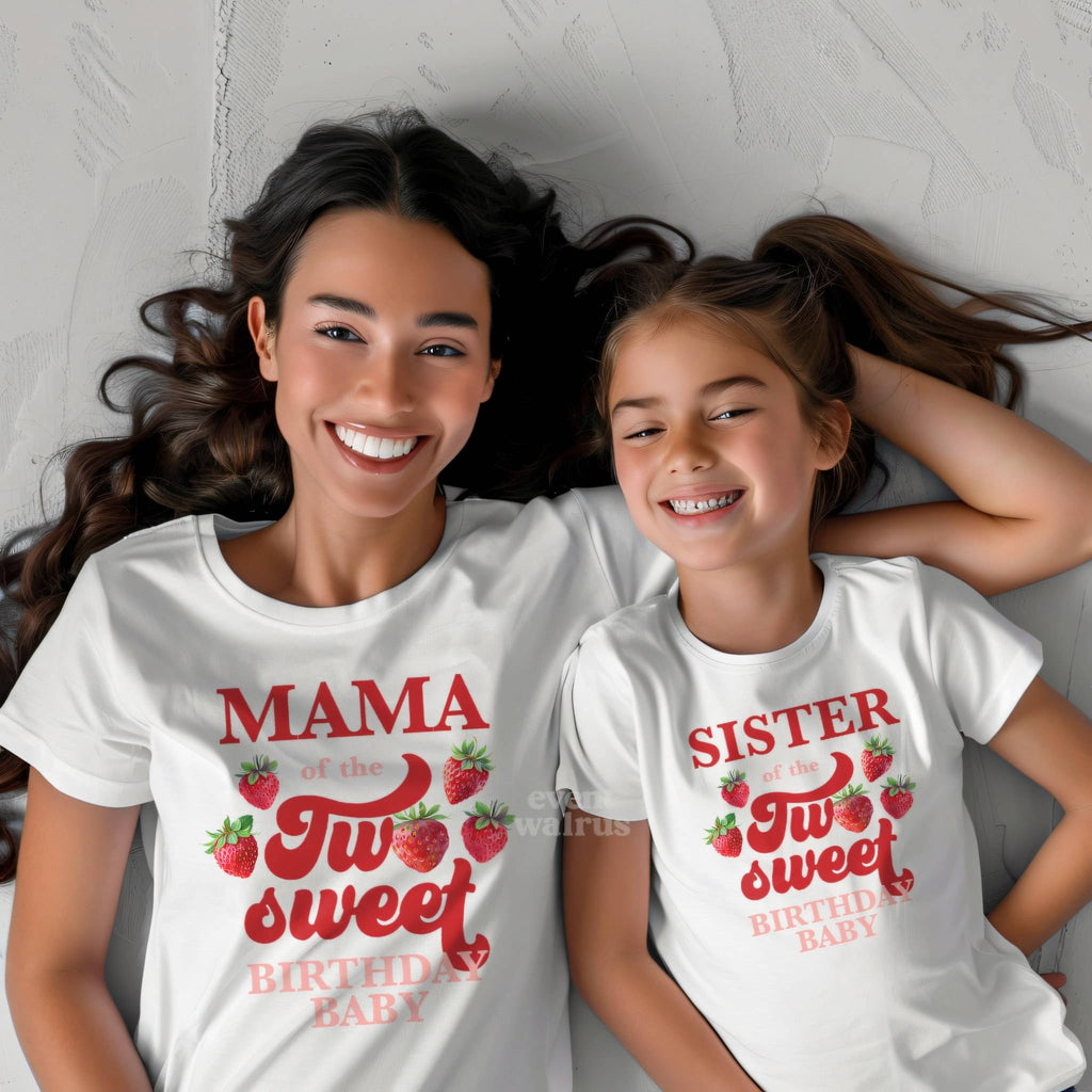 Little girl lying beside her mom in white Sister and Mama strawberry shirts.