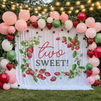 Strawberry vine backdrop on a lawn under string lights with pink and red balloons.