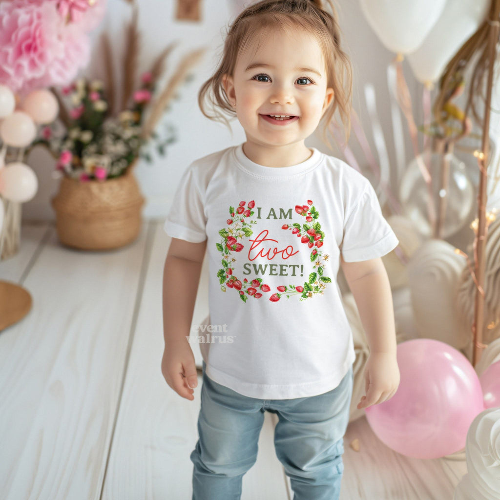 Smiling toddler girl at a pink party in a white I Am Two Sweet tee.