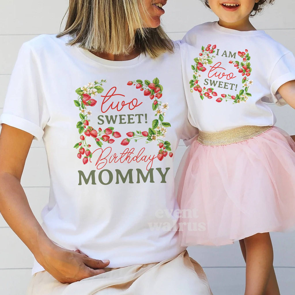 Little girl in a tutu holding Mom's hand, both in white strawberry vine Two Sweet shirts.