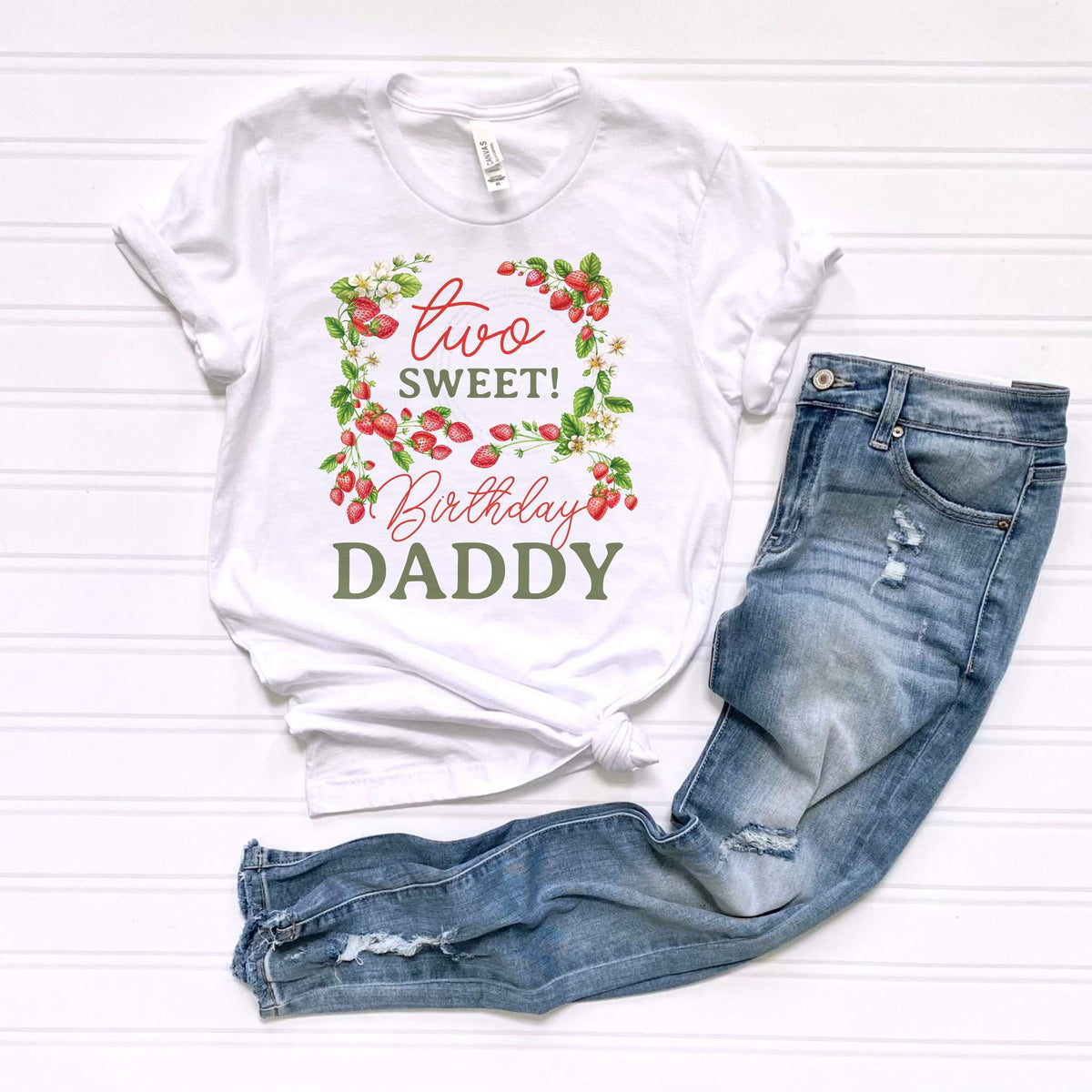White Two Sweet Birthday Daddy tee laid flat beside jeans.