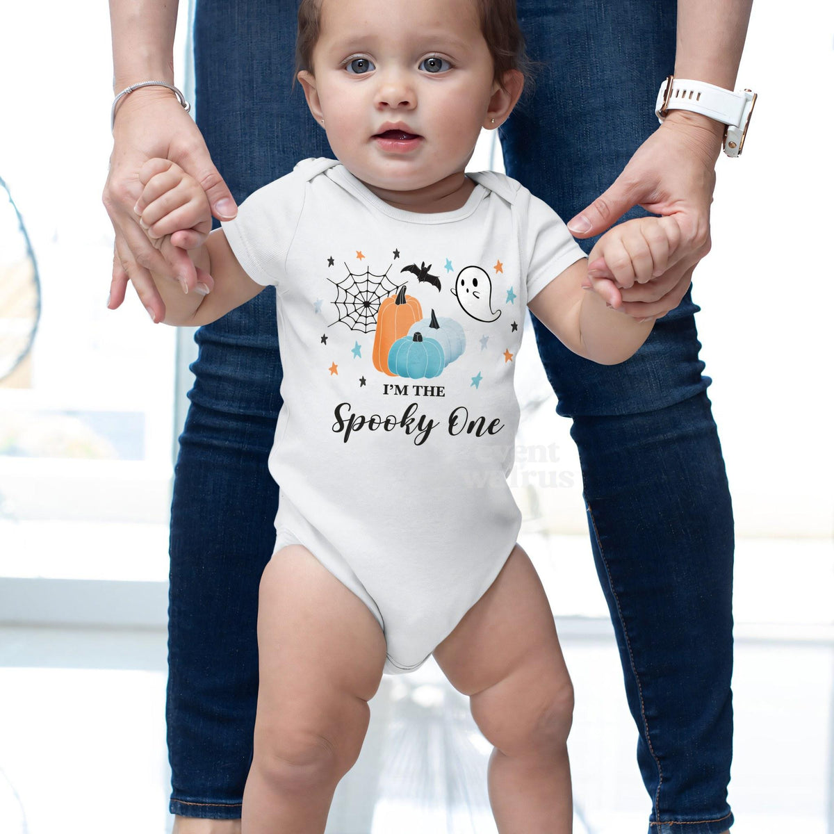 Baby taking steps while holding Mom's hands, in a white I'm the Spooky One bodysuit.