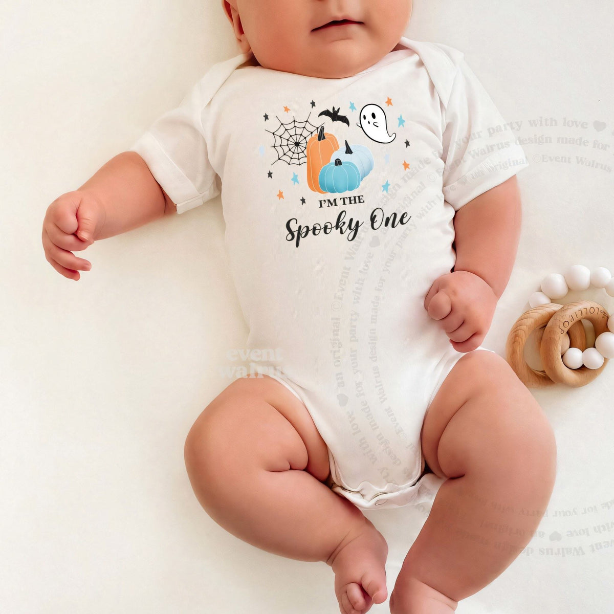 Baby lying on a white blanket in a white I'm the Spooky One bodysuit.