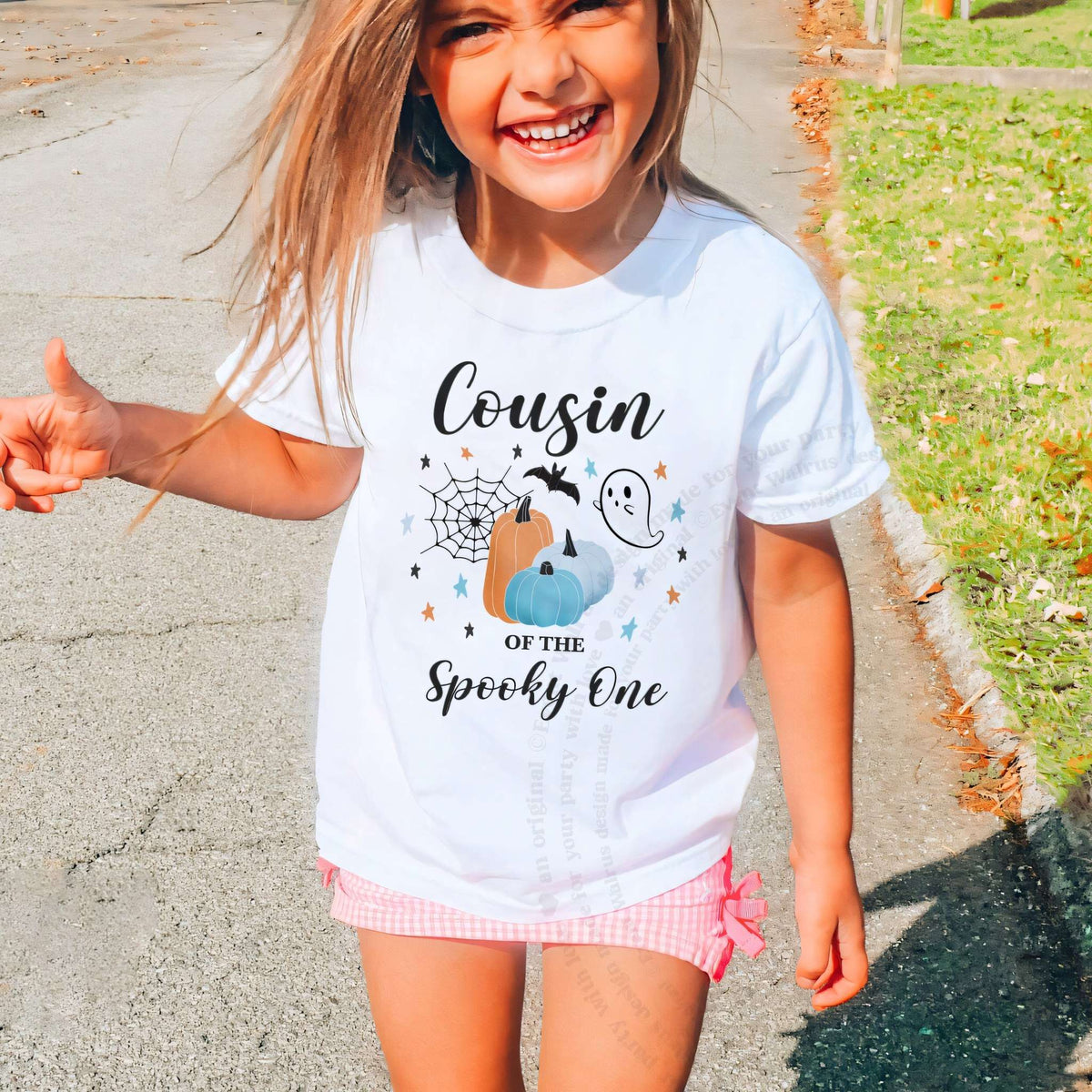 Laughing girl outdoors in a white Cousin of the Spooky One kids tee.