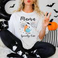 Woman in ghost leggings wearing a Mama of the Spooky One shirt with teal and orange pumpkins.