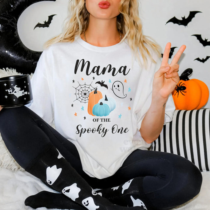 Woman in ghost leggings wearing a Mama of the Spooky One shirt with teal and orange pumpkins.