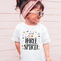 Girl in sunglasses and a pink headband wearing a white I'm the Three Spirit shirt.