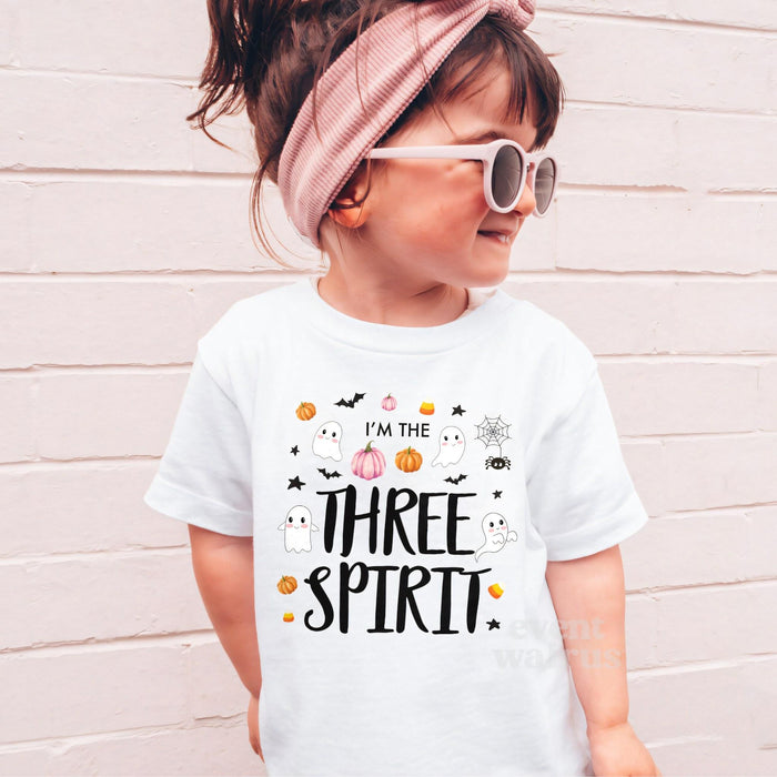 Girl in sunglasses and a pink headband wearing a white I'm the Three Spirit shirt.