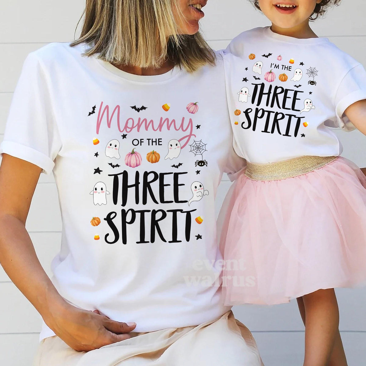 Mom holding hands with her little girl in a tutu, both in white Three Spirit shirts.