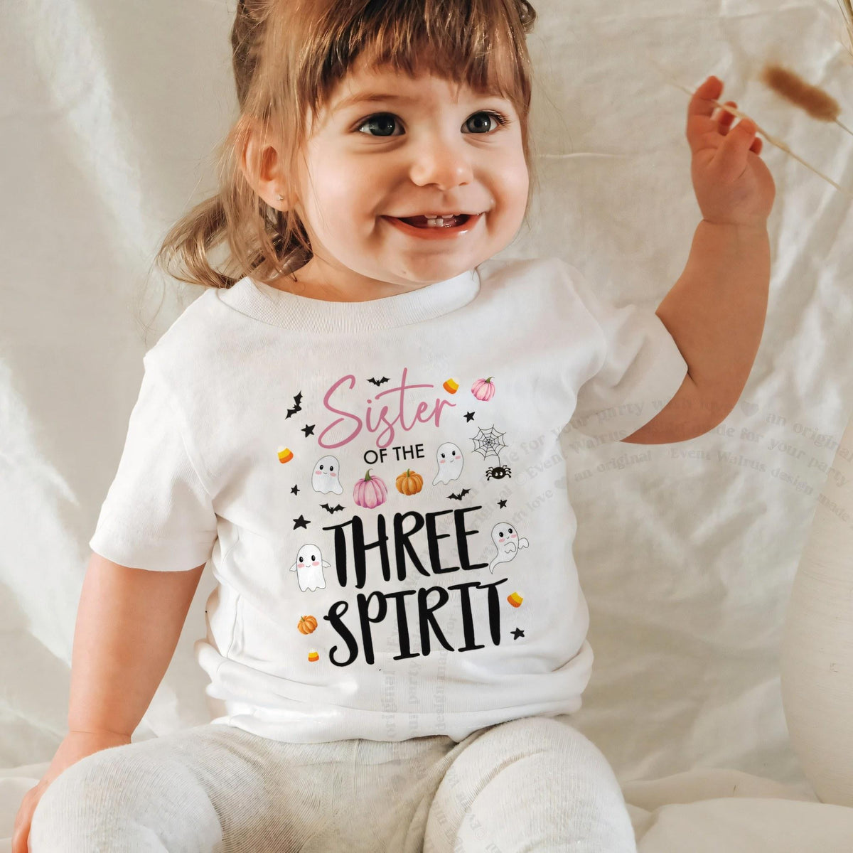Laughing baby girl in a white Sister of the Three Spirit baby tee.