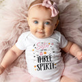 Baby girl with a pink bow on tulle in a white Sister of the Three Spirit bodysuit.