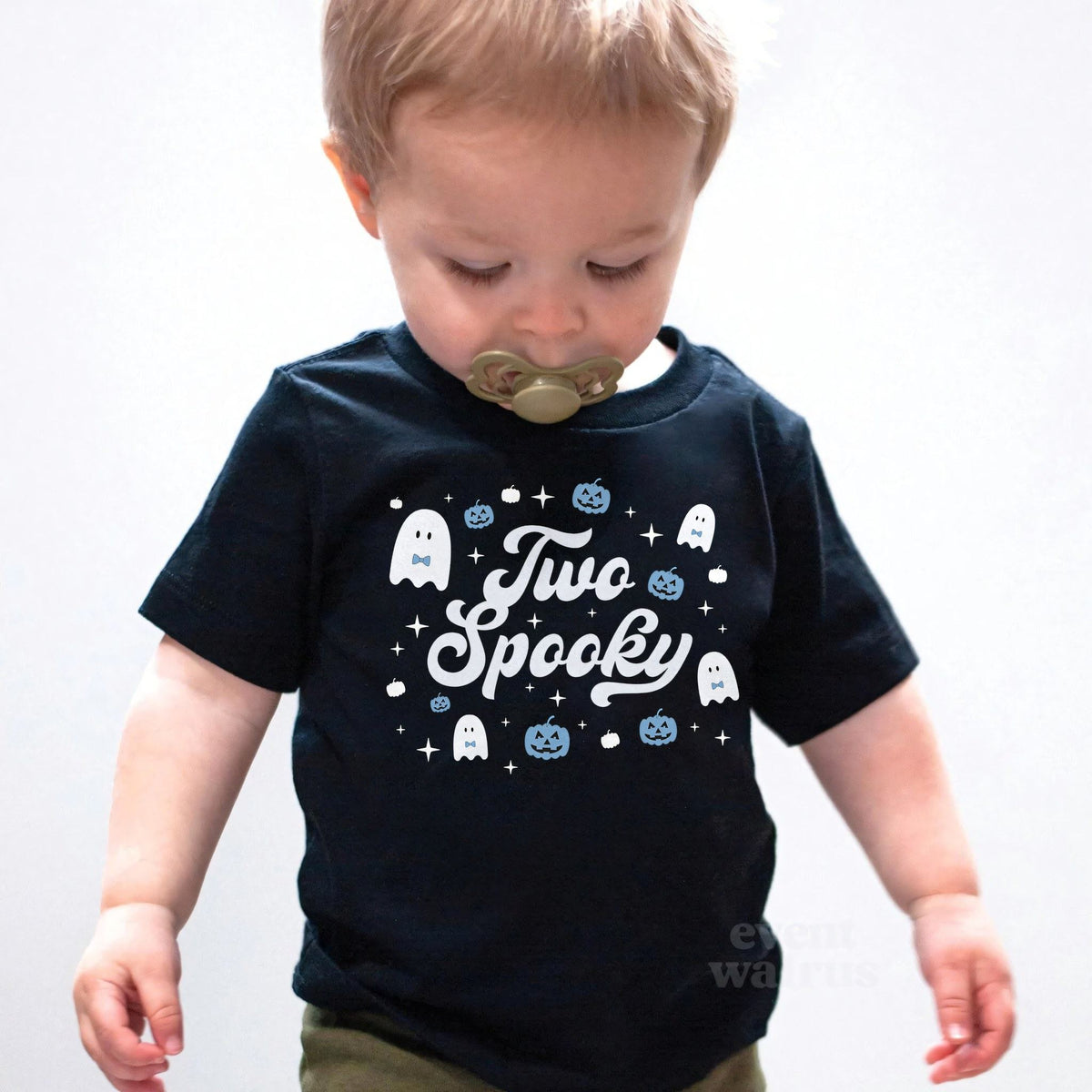 Toddler boy with a pacifier wearing a black Two Spooky ghost birthday shirt.