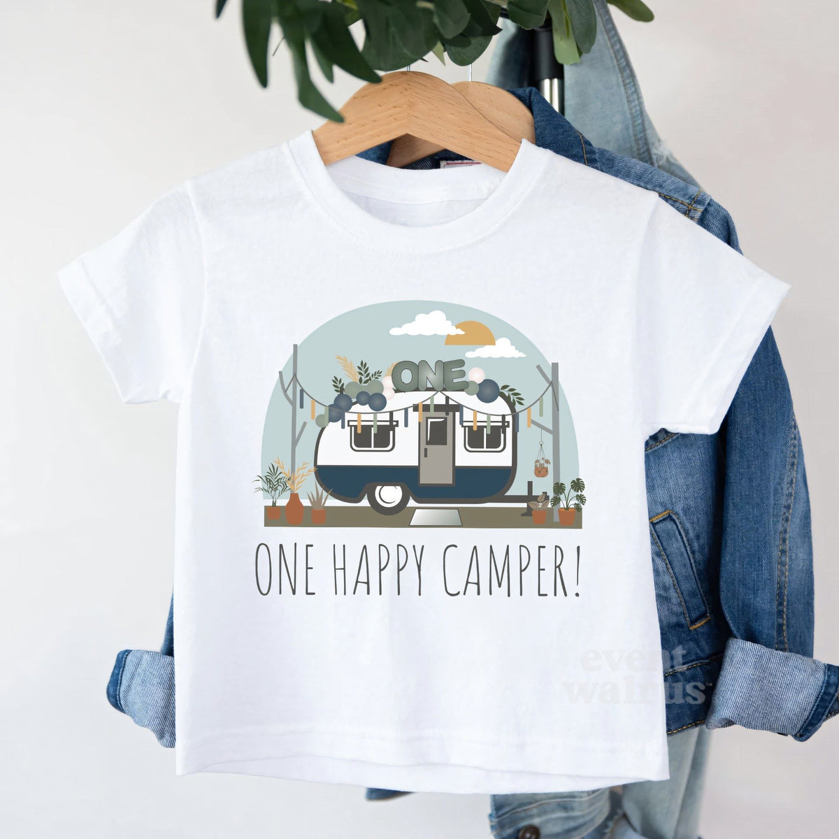 White One Happy Camper toddler tee on a hanger over a denim jacket.