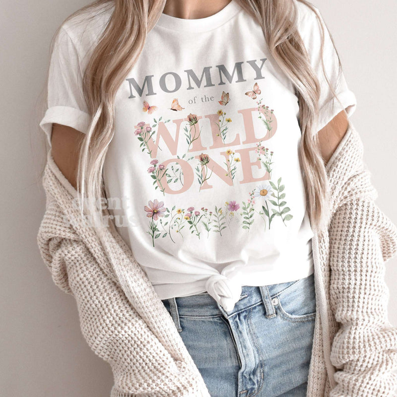 Mom wearing a white Mommy of the Wild One shirt with pink watercolor wildflowers and butterflies.