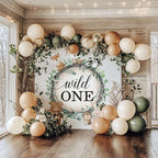 Wild one first birthday backdrop in a wood room with sage, cream and tan balloons.