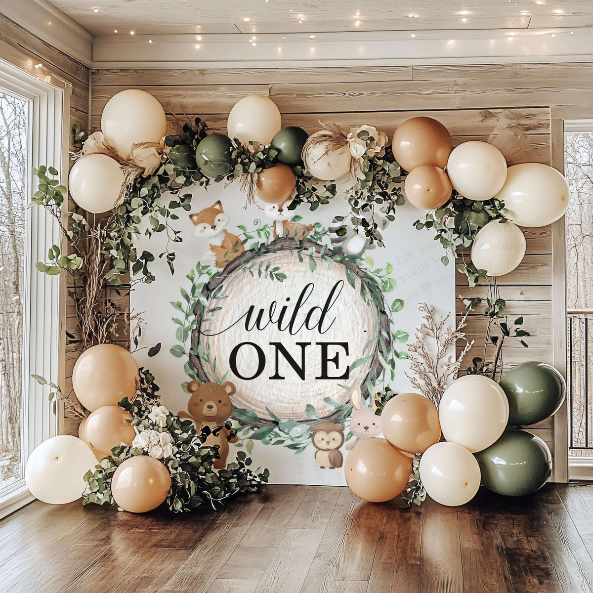 Wild one first birthday backdrop in a wood room with sage, cream and tan balloons.