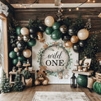 Wild ONE woodland backdrop in a dark cabin with green, black and gold balloons and teddy bears.
