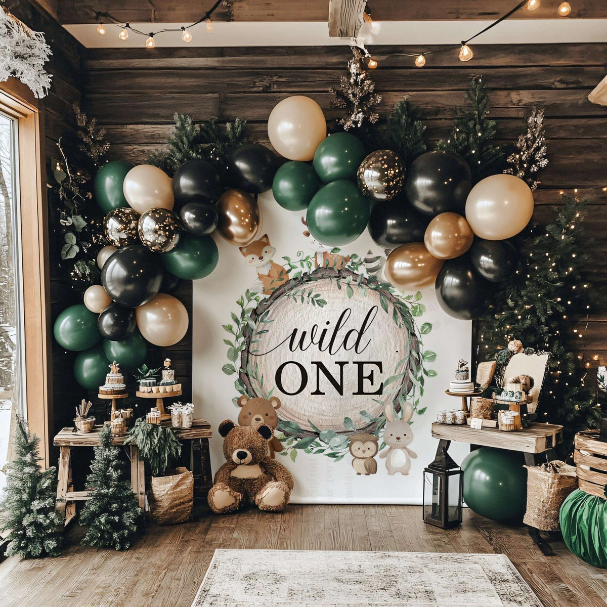 Wild ONE woodland backdrop in a dark cabin with green, black and gold balloons and teddy bears.