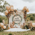 Woodland animals wild one backdrop in a meadow with peach balloons and a flower garland.