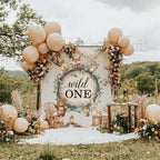 Woodland animals wild one backdrop in a meadow with peach balloons and a flower garland.
