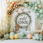 Woodland wild one backdrop with tall wildflowers, mint balloons and a white chair.