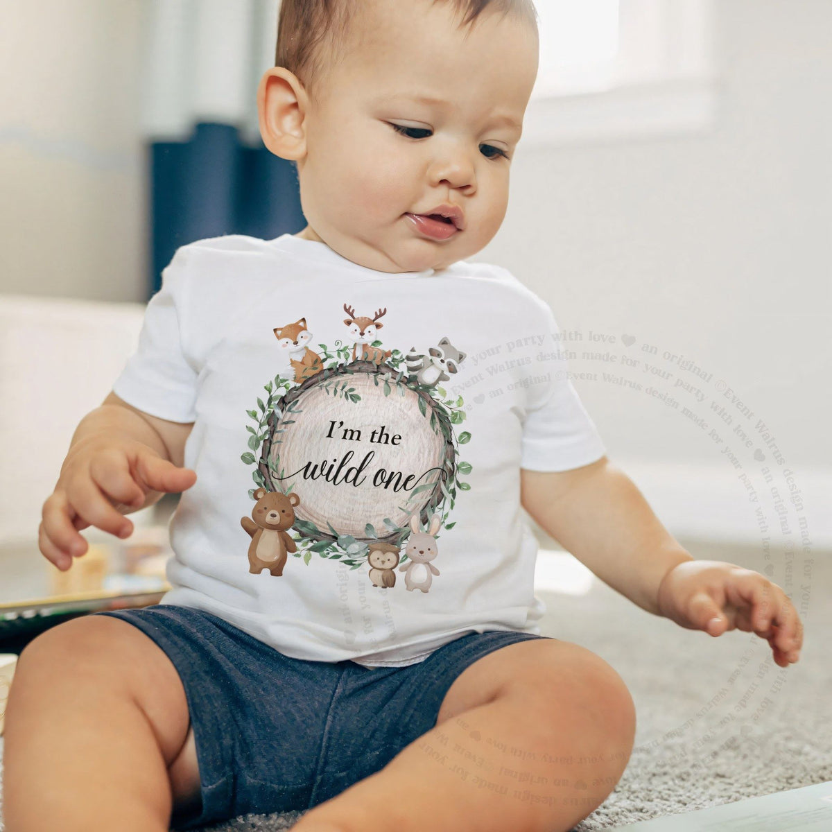 Baby boy sitting on a rug in a white I'm the Wild One woodland baby tee.