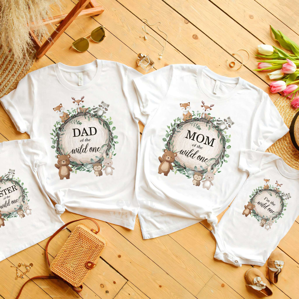 Dad, Mom, Sister and baby woodland Wild One shirts laid out on a wooden floor.