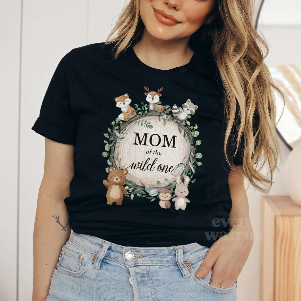 Woman in a black Mom of the Wild One shirt with the woodland animal wreath.