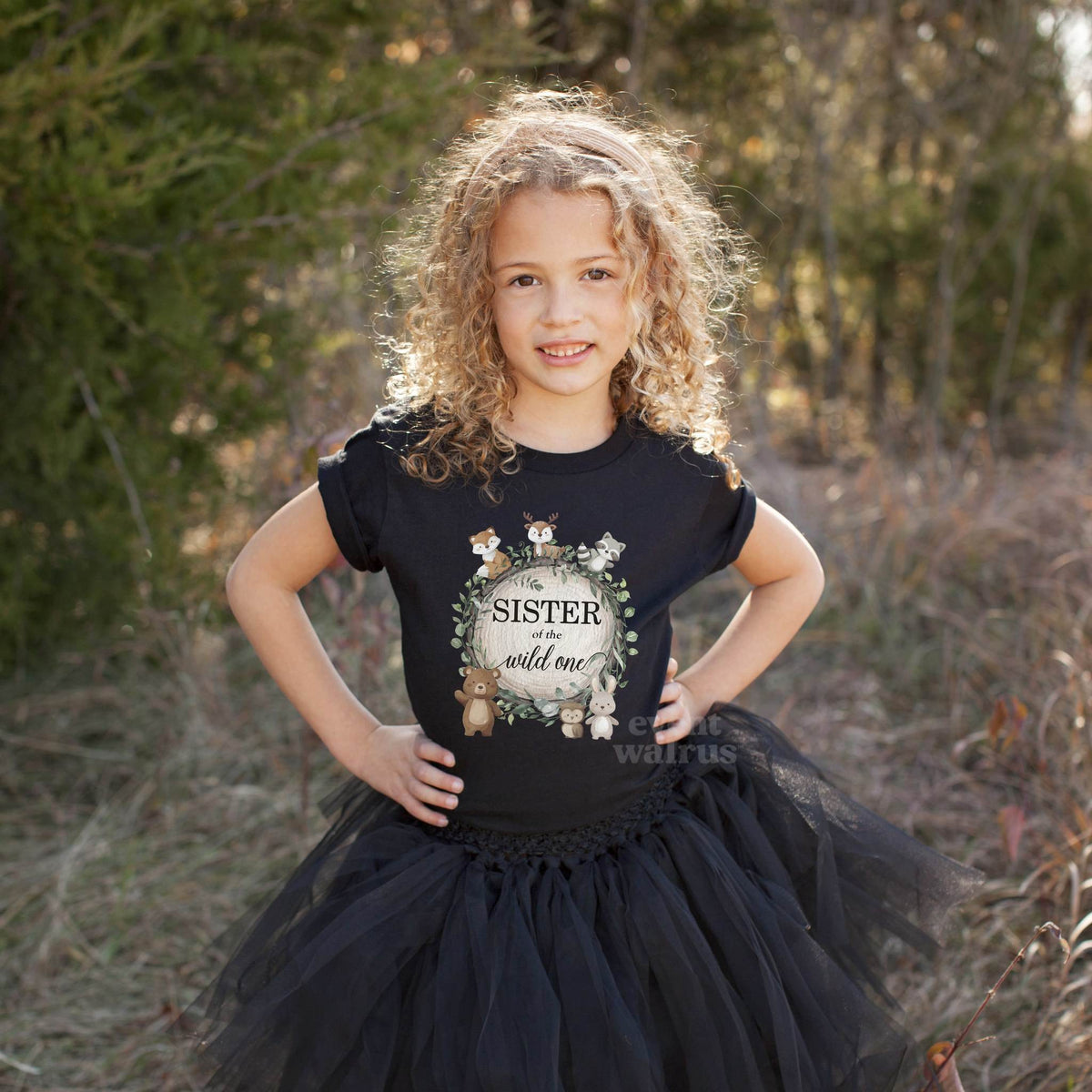 Girl in a black tutu and a black Sister of the Wild One woodland shirt in a field.